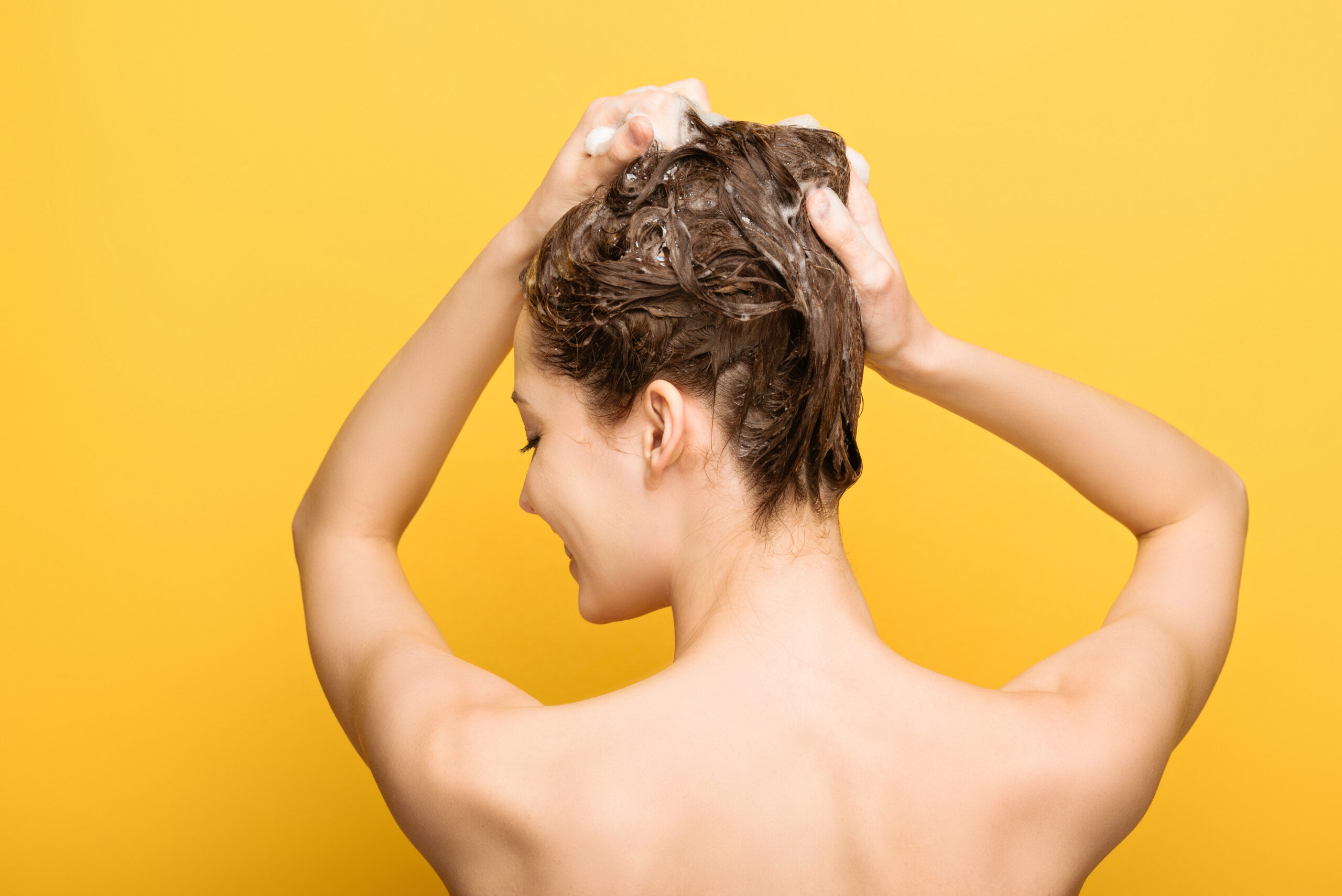 A woman takes a shower and rubs her scalp after using conditioner for the best haircare results.