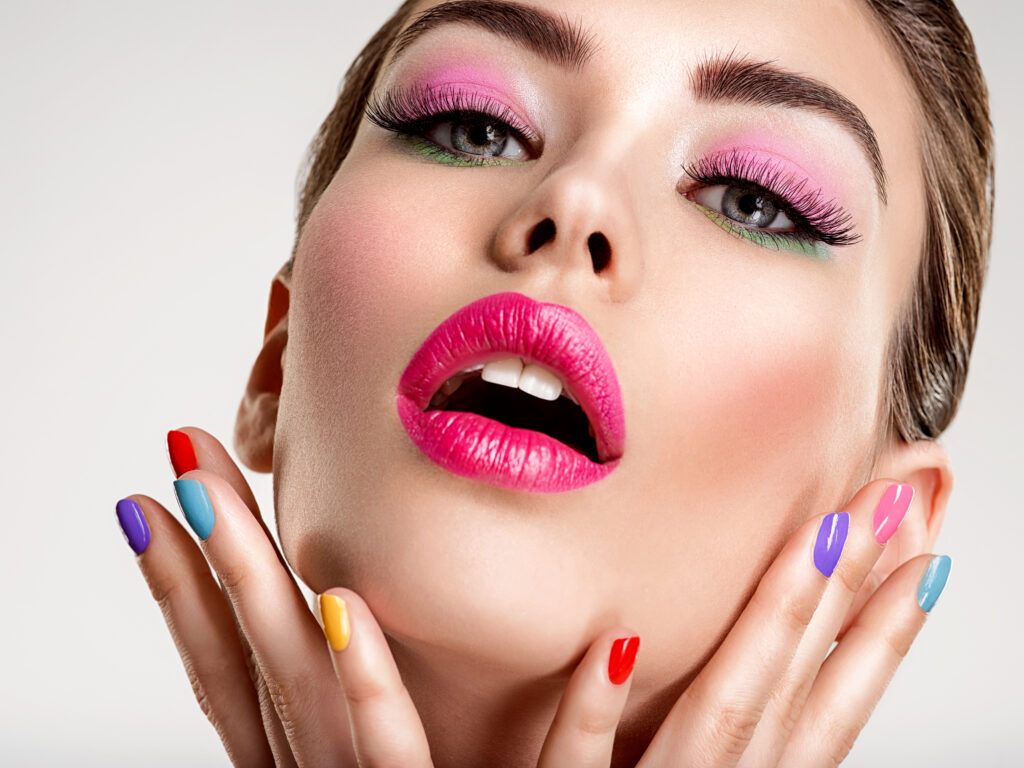 Beautiful fashion woman with a colored nails. Attractive white girl with multicolor manicure. Glamour fashion model with bright gloss make-up posing at studio. Stylish fashionable concept. summer 2023 nails