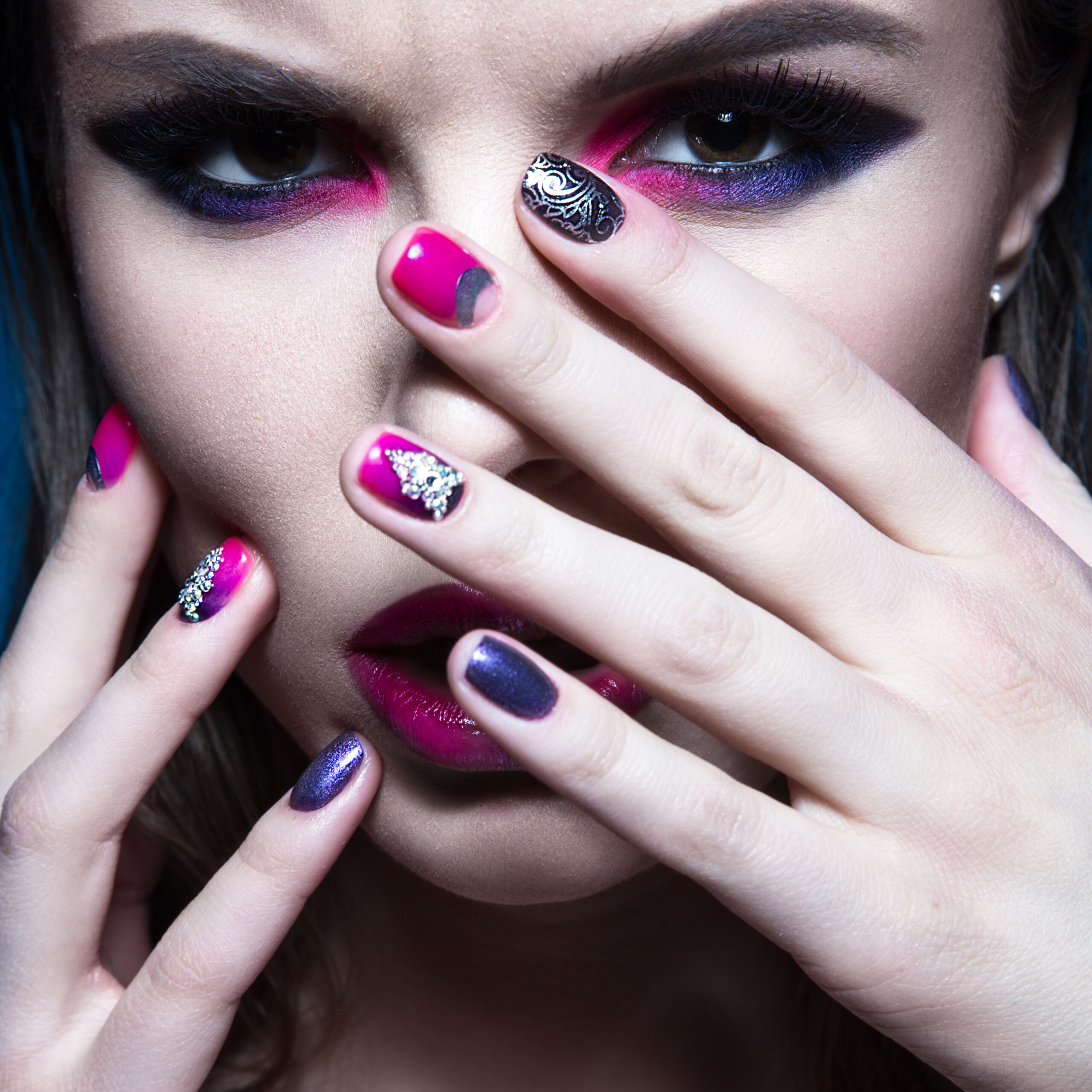 Beautiful girl with bright creative fashion makeup and colorful nail polish. Art beauty design. Photos shot in studio