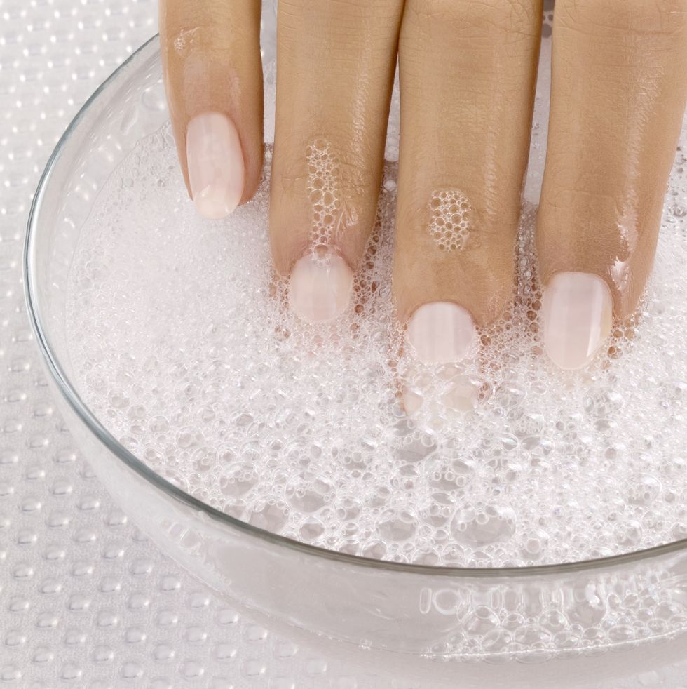 A woman puts on an acrylic manicure and soaks it with acetone to make it stickier