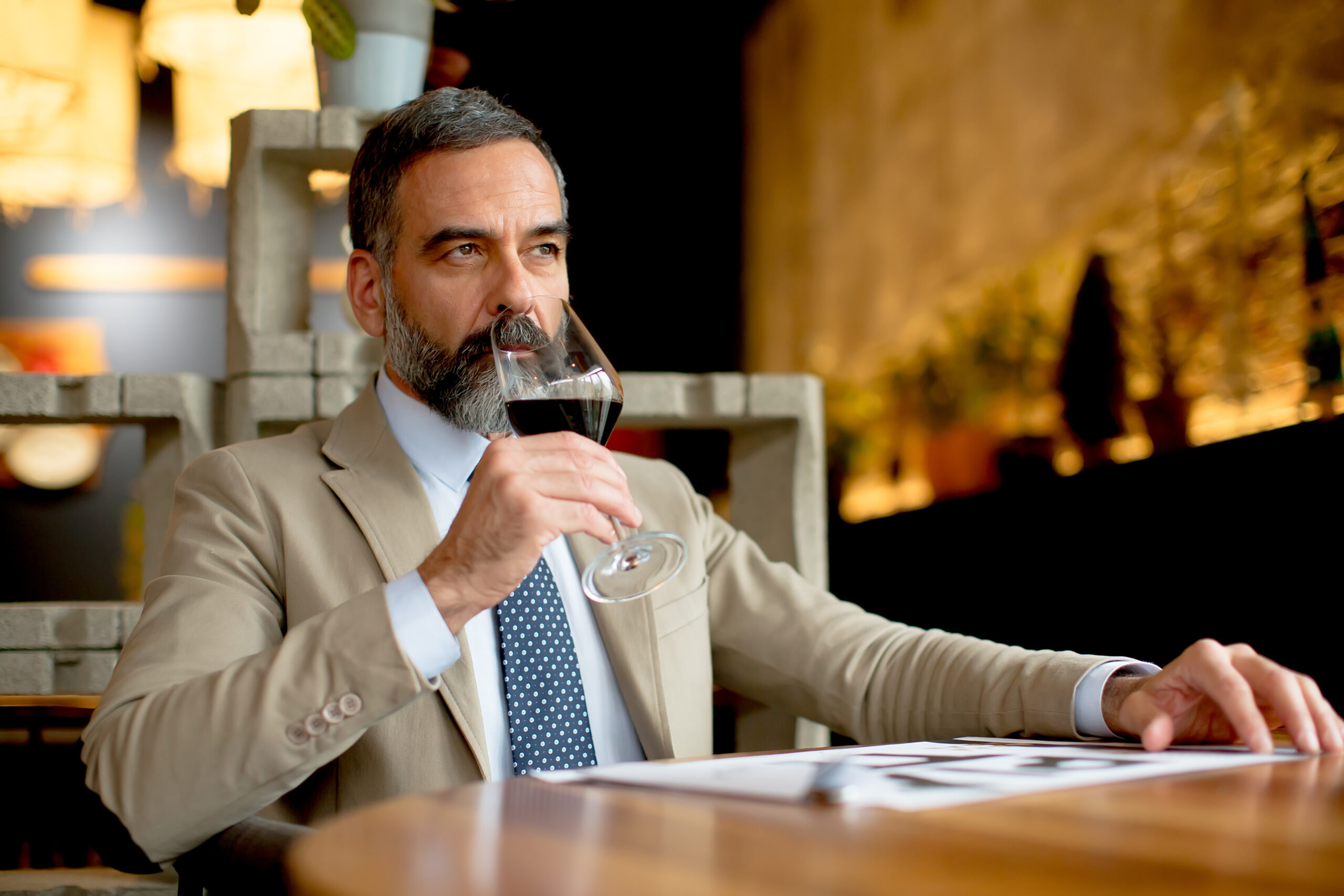 Handsome middle aged businessman drinking red wine in restaurant