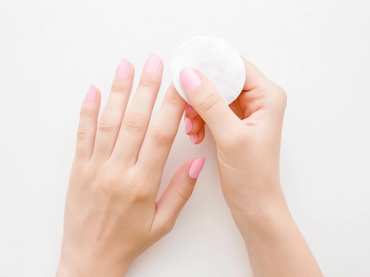 Woman removing manicure with soft cotton