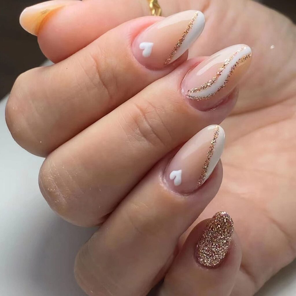 A woman's hand with round nails featuring a beige and gold design.