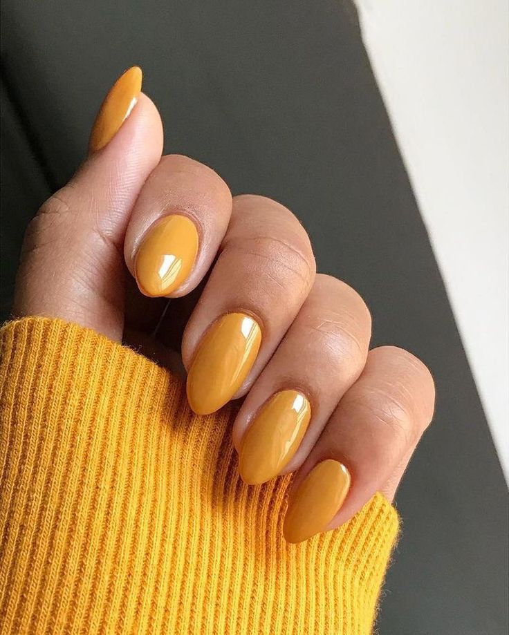 Woman wearing mustard yellow manicure and matching sweater