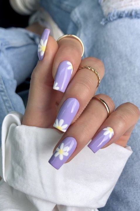 A lady with lavender nails adorned with white daisies.