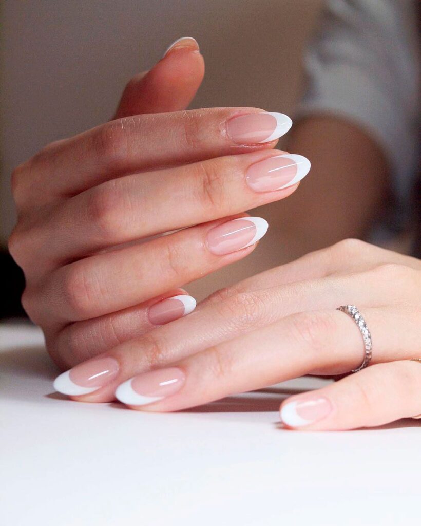 A woman with round French nails and a ring on her finger.