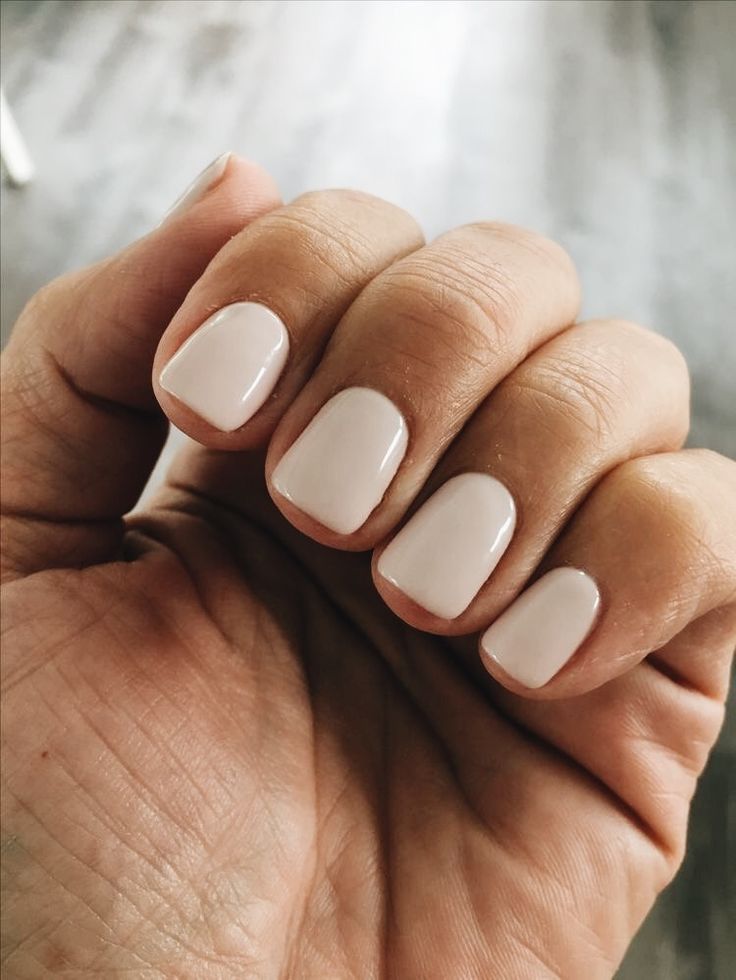 A woman's hand holding a nude nail polish. Nude Nails