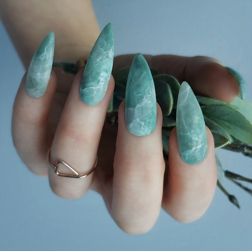 A woman's hand applying a beautiful and attractive marble manicure