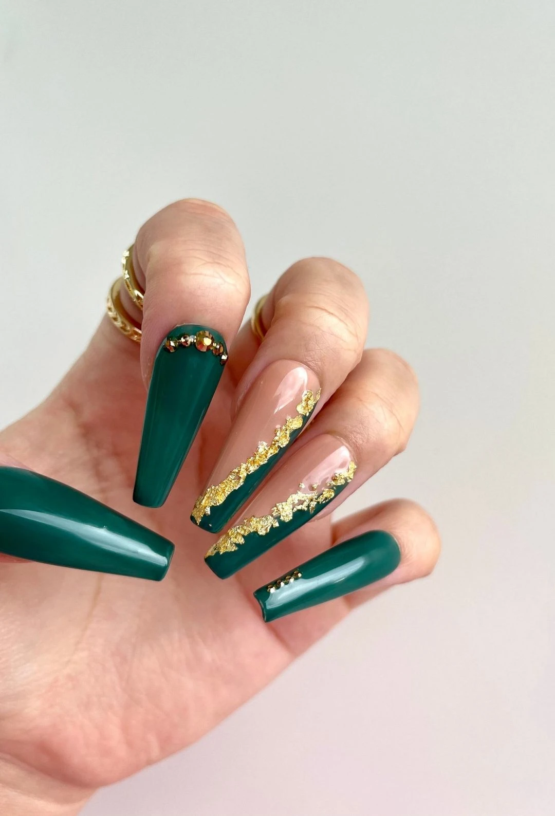 Beautiful and innovative green nail shade with golden accessories as nail art