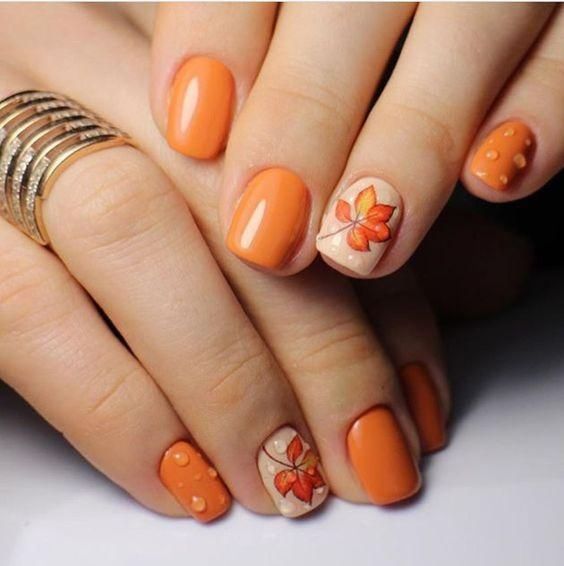 A faceless woman's nails with brown fall leaf designs on her nails. Fall Nail Designs