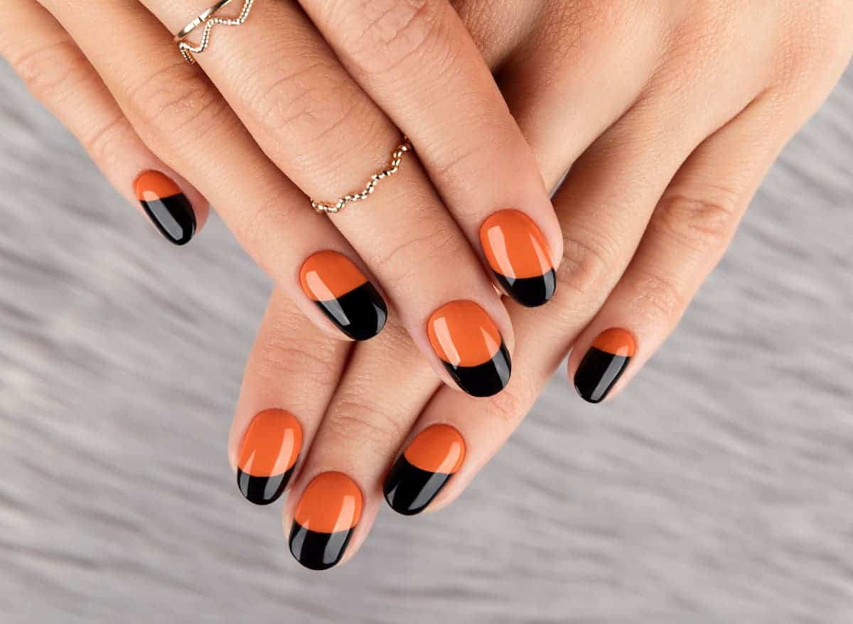 A woman's hands with the warm-toned orange and black nail shades.