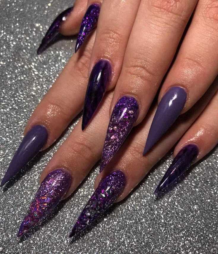 A woman's nails with a purple and violet manicure with sparkles