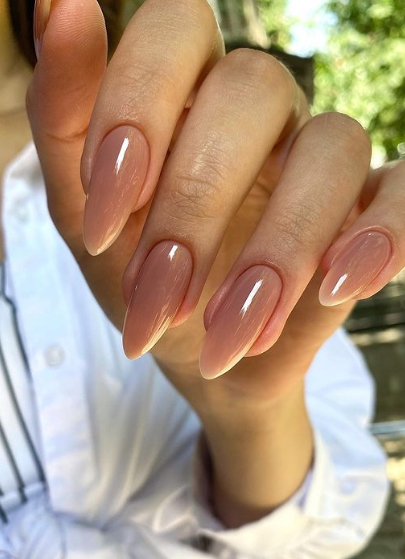 A woman's hands exhibit stiletto nails adorned with neutral nail shade.