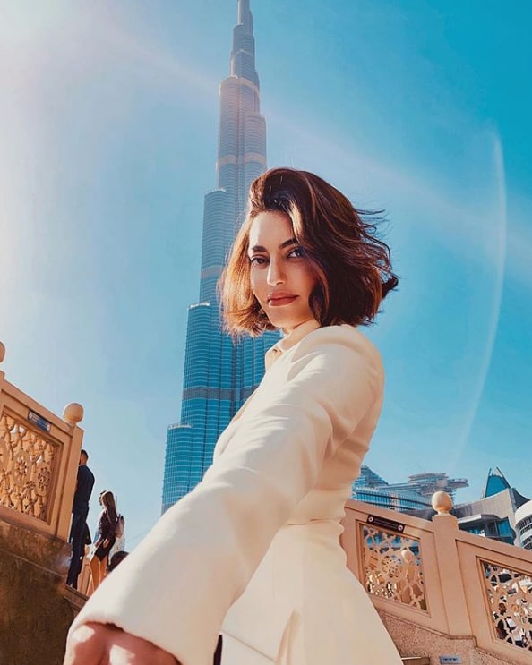 Karen, an influencer in the world of beauty, wears a white dress, with the Burj Khalifa behind her