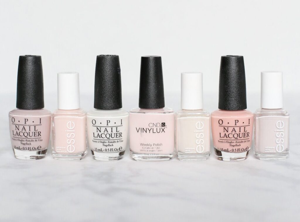 A row of Opi nail polishes, featuring both hybrid and traditional nail options, elegantly displayed on a marble countertop.