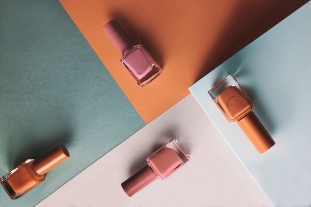 Multi-colored nail polish on pastel colors geometric pattern background. Color-changing nail polish