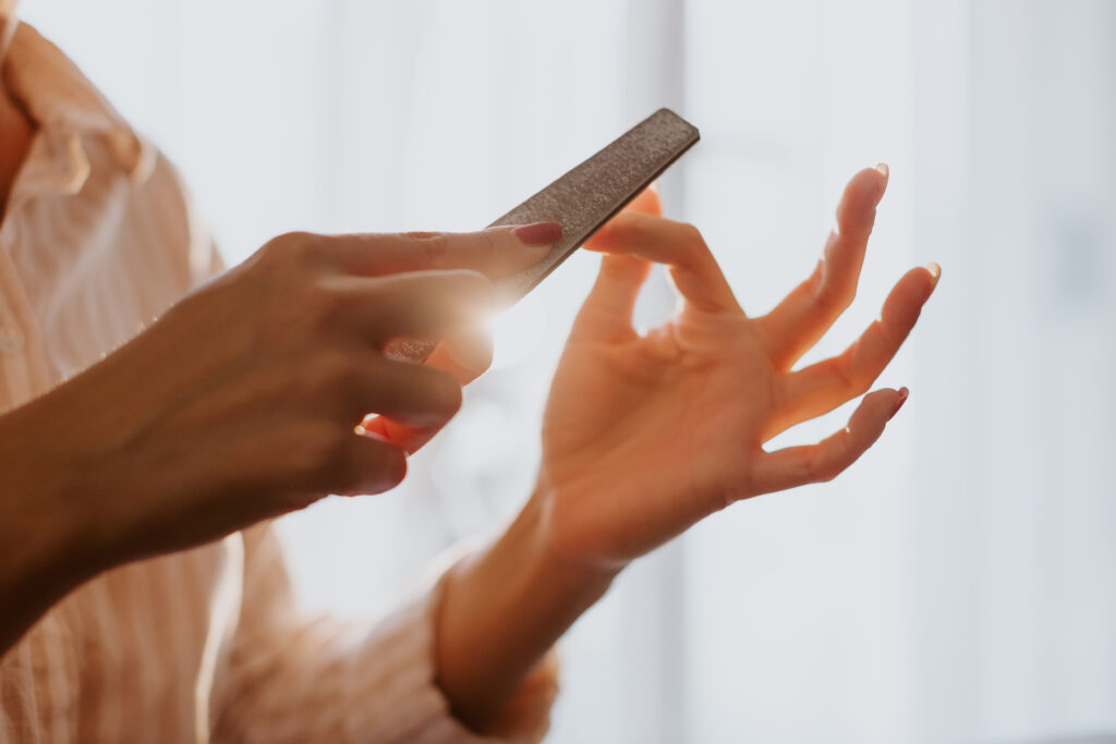 filing nails in proper way. Woman doing manicure. Home nail care. Red nails