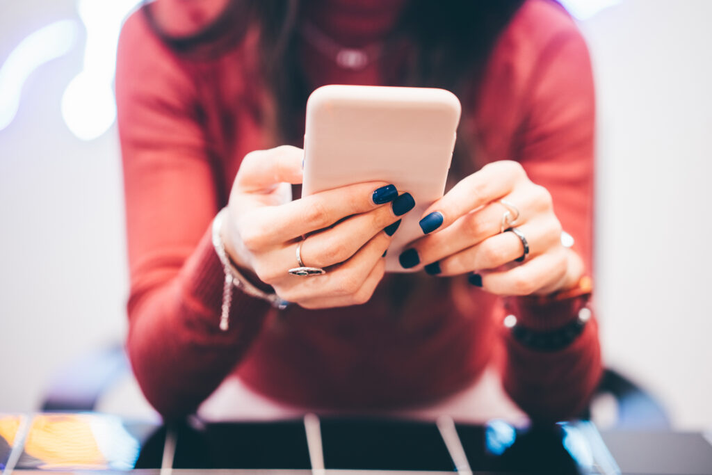 Close-up mobile phone. Female hands with blue manicure holding a smart phone.
