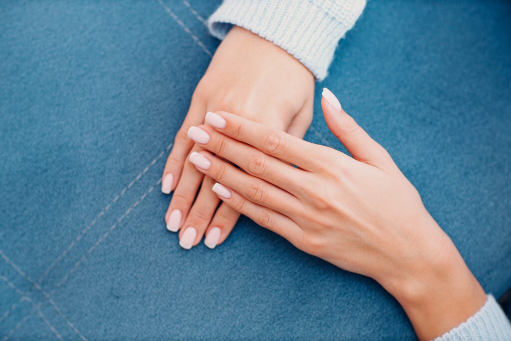 Female hand fingers nails with manicure after nail salon procedure.