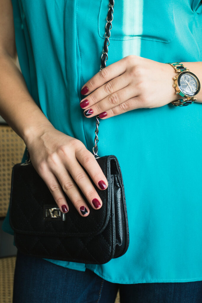 Female nails with red nail polish and a beautiful black handbag