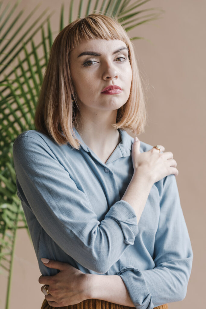 Portrait of a beautiful woman wearing a blue shir with baby bangs hair cut. 2024 hair trends