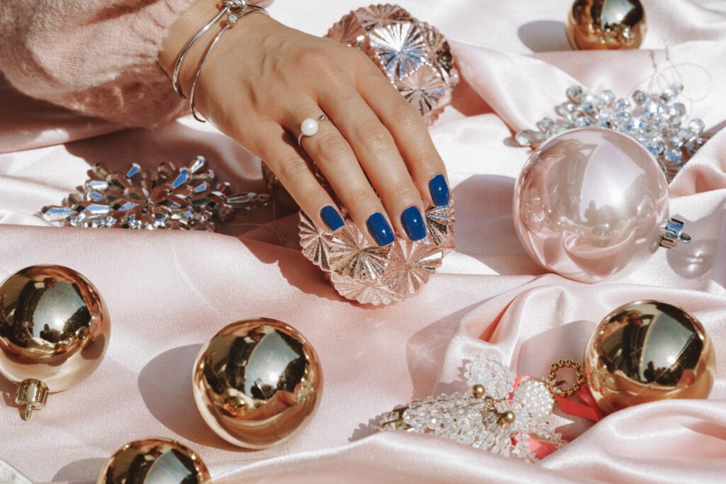 Woman's hand in blue manicure with Christmas decorations