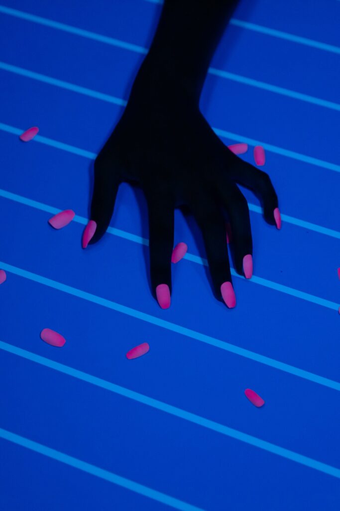 Black woman's hand with pink nail polish on a blue background