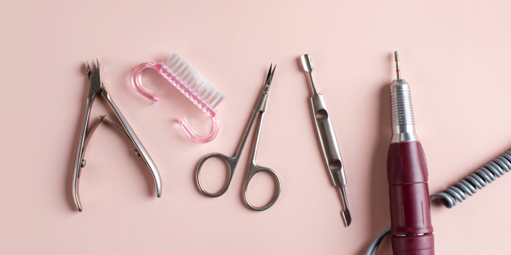 Set of metal tools for manicure and pedicure and nail fraser on light pink background view from above template for nail art designs