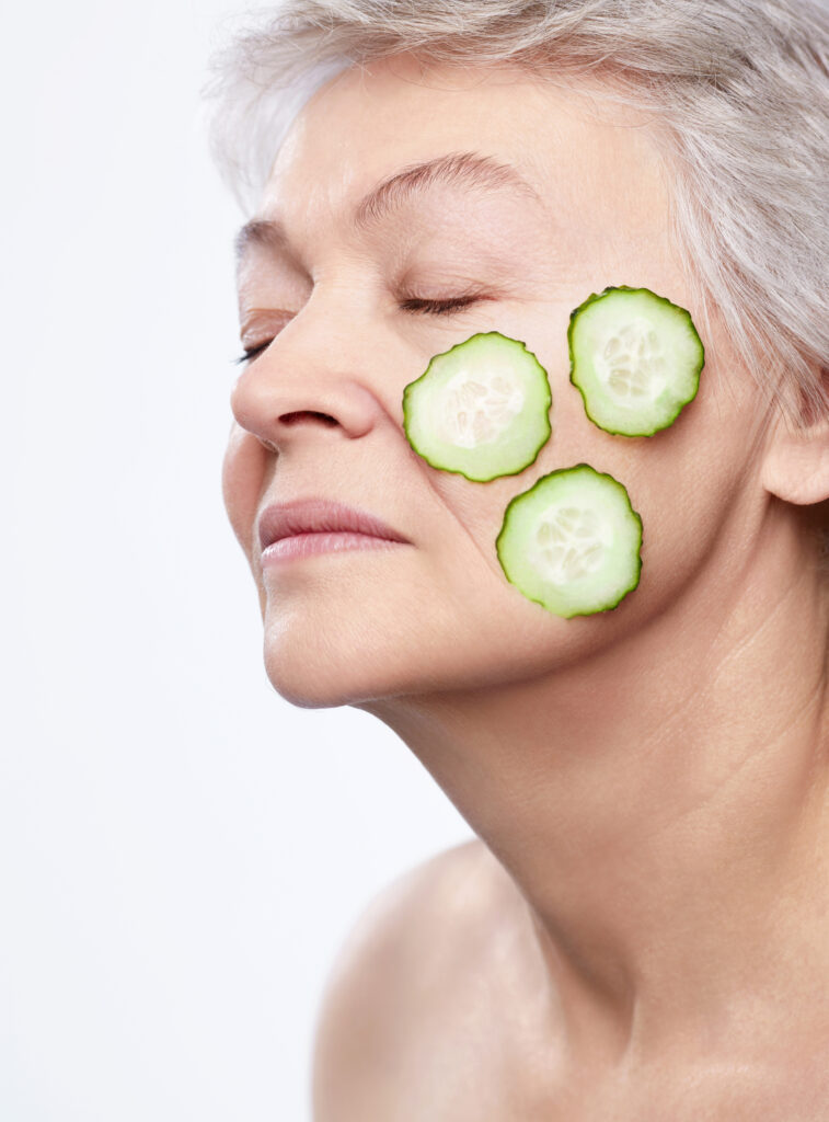 Elderly woman with a mask of cucumber on a white background to skincare