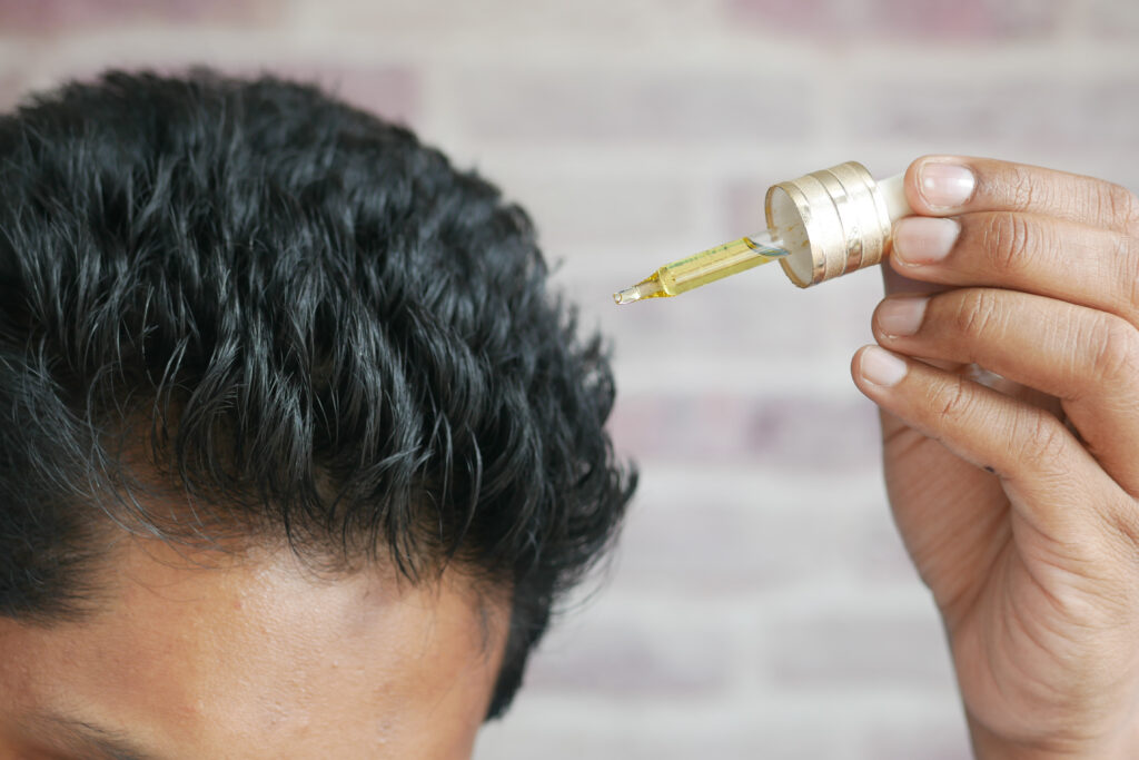 young men applying essential oils on his hair .