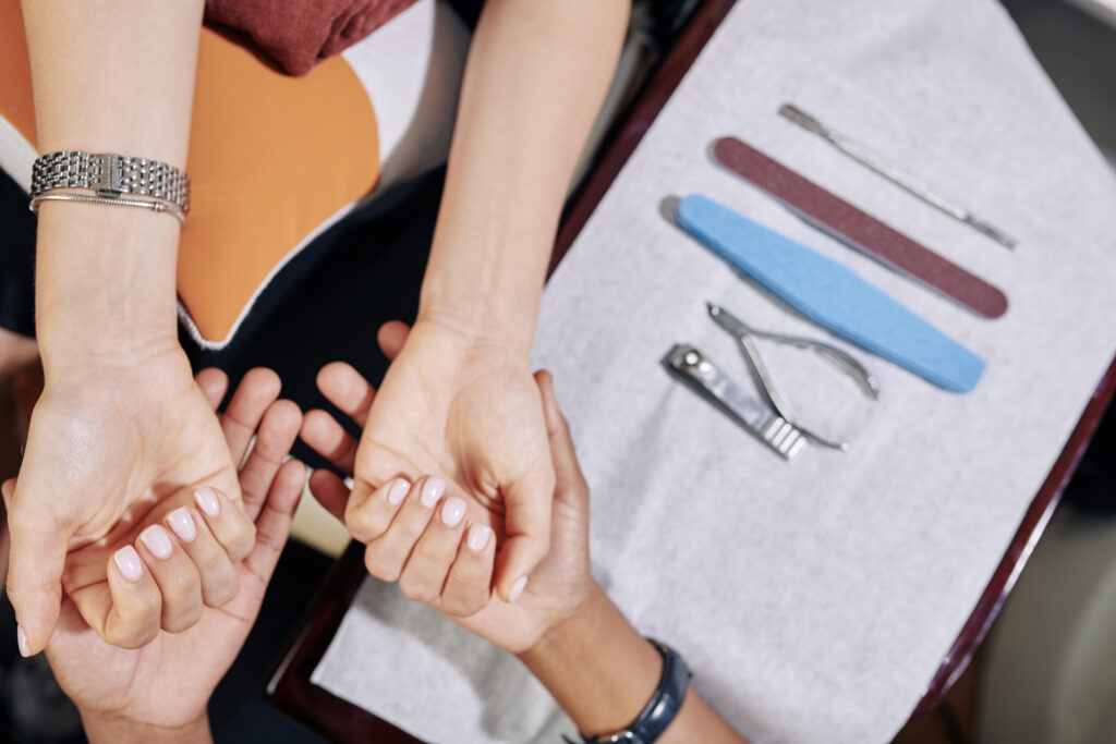 Manicurist examining hands of female client before starting manicure process, view from above. long and healthy nails