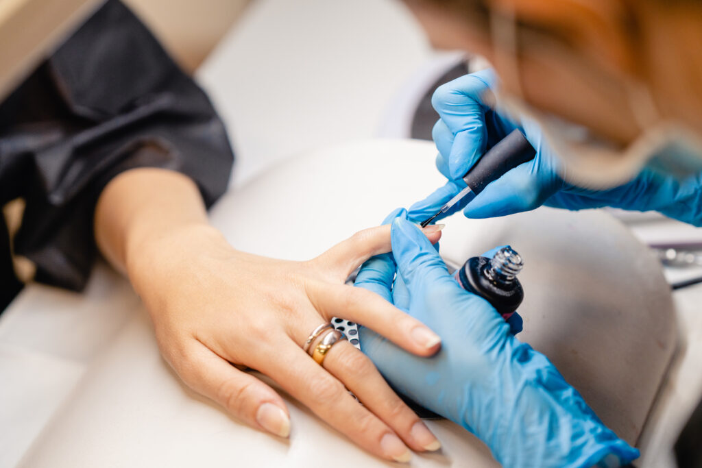 Manicurist paints nails with gel polish on girl nails. nail service.