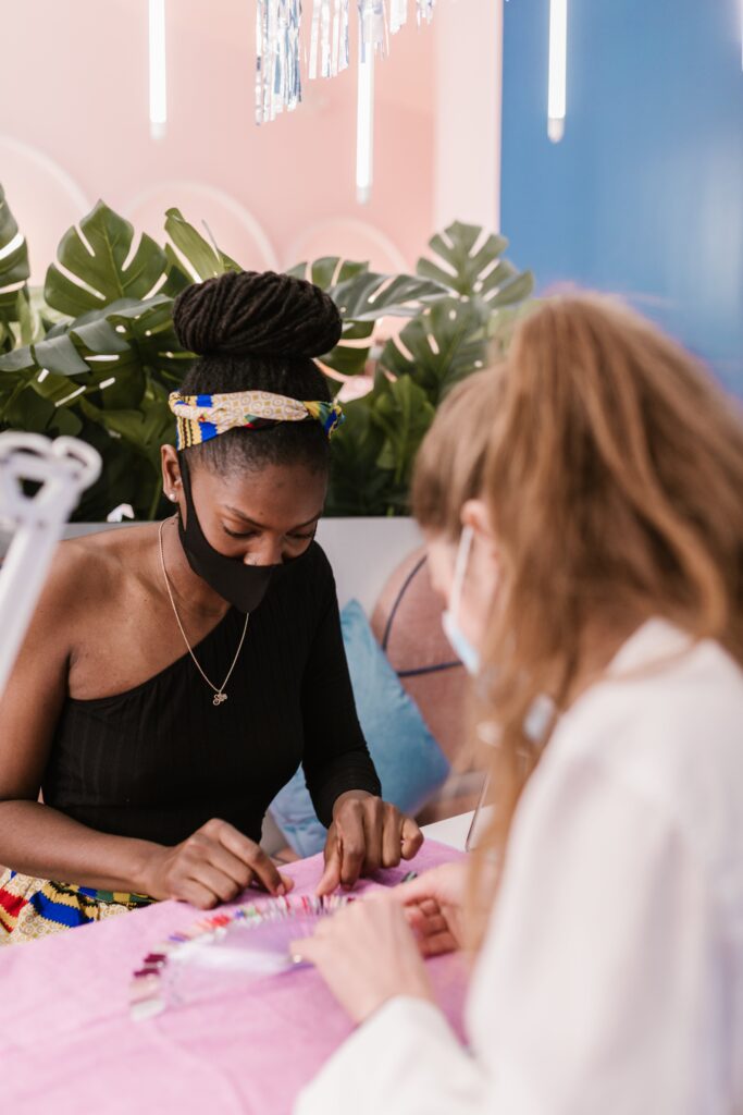 A beautiful girl is choosing her nail service with a nail technician to suit her lifestyle