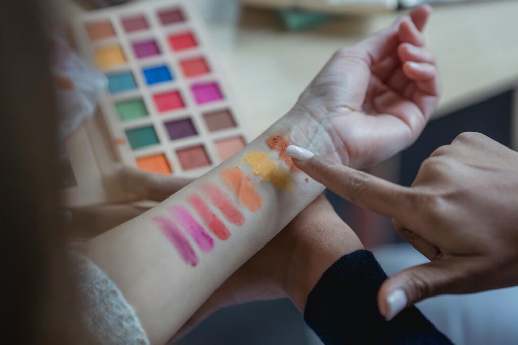 A faceless woman is trying colorful eyeshadows on her hands to know which one suit her skin tone