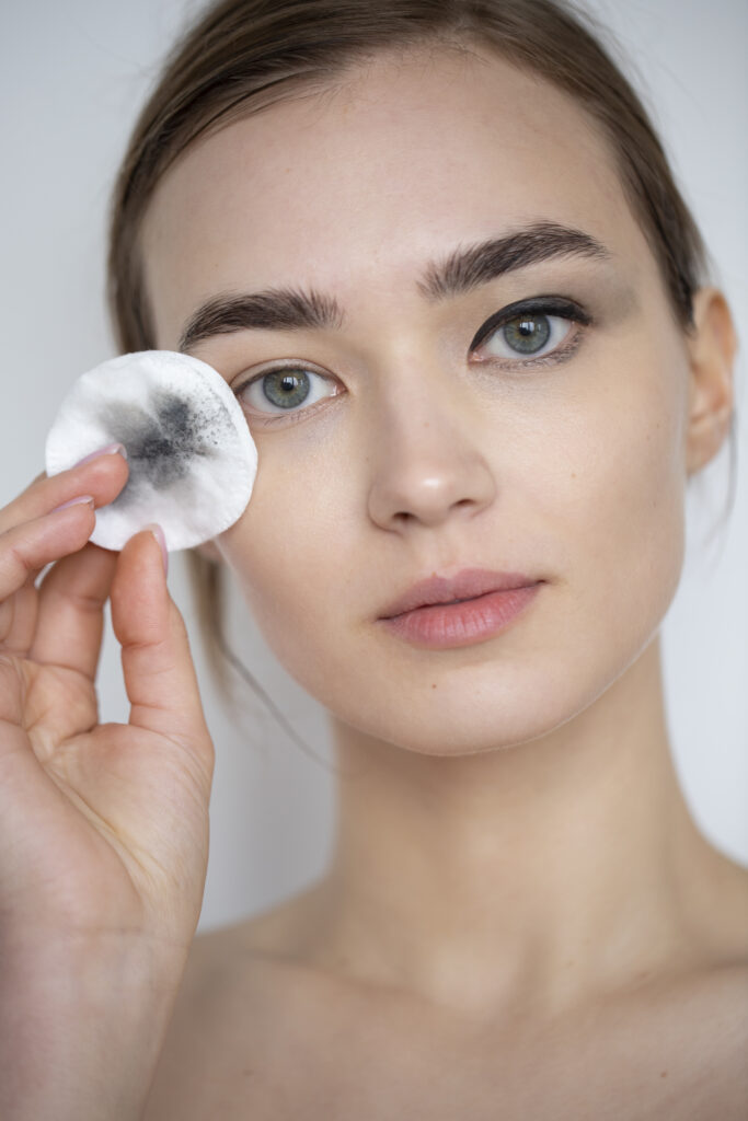 a beautiful woman is removing eyeliner at home with cotton pads