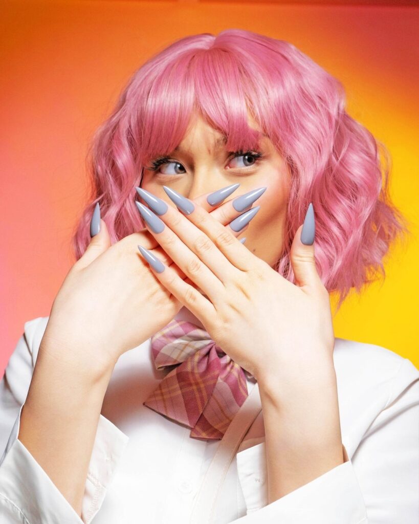 A beautiful woman with wearing press-on nail tips, the tips are long and painted in light blue nail polish shade