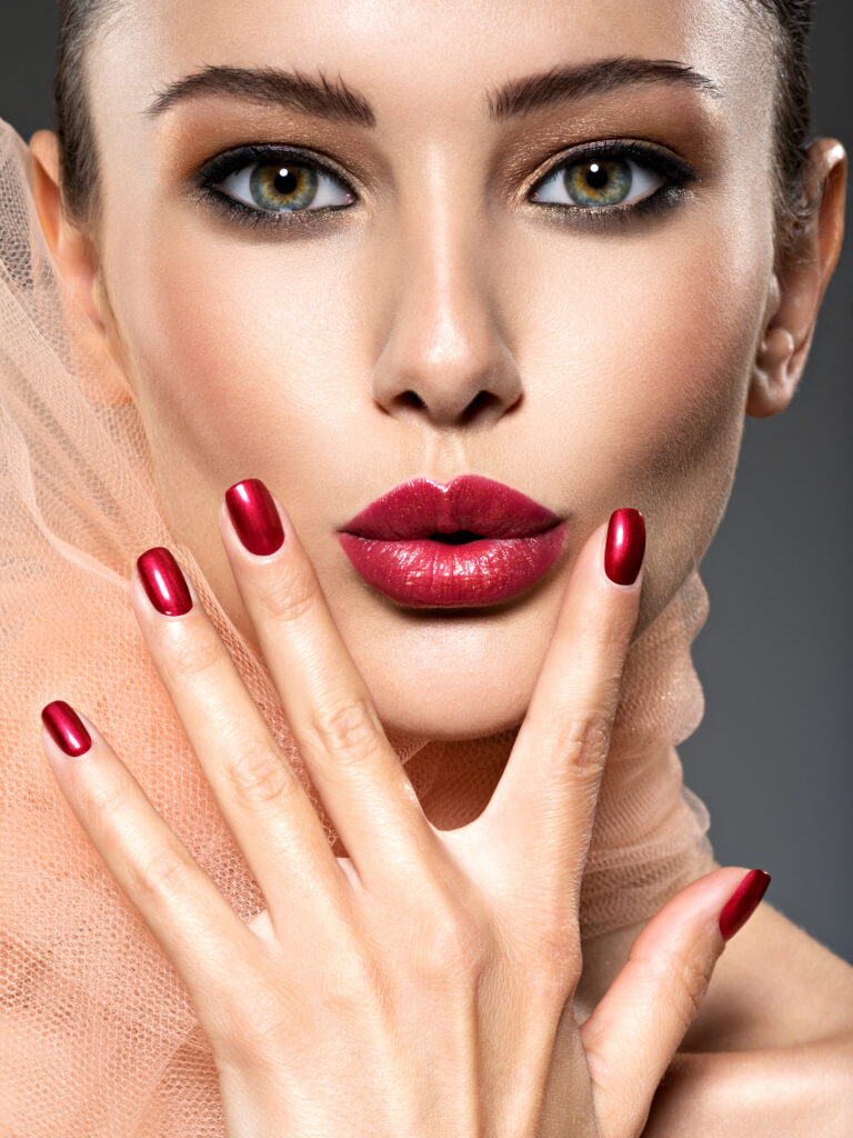 Beautiful woman with brown makeup and red nails and lips. Fashion model posing at studio