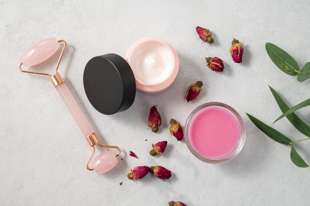 Face or body cream, soap and massager on a light background. The concept of care cosmetics with rose and eucalyptus. Health and beauty. Top view.