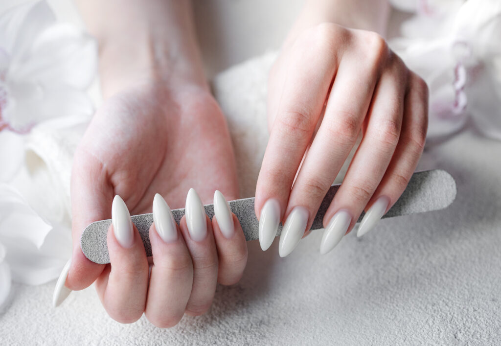 Beautiful hands of a young woman with white manicure on nails. Female hands on a towel and white orchids flowers.