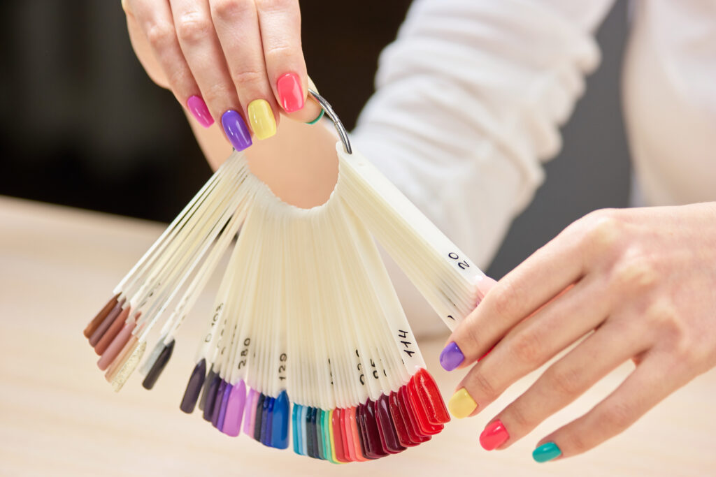 Nails colors samples in female hands. Girl with beautiful summer manicure holding nails colors samples. Big variety of nails colors.