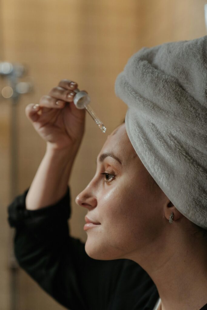 A beautiful girl is applying a facial serum to her face.