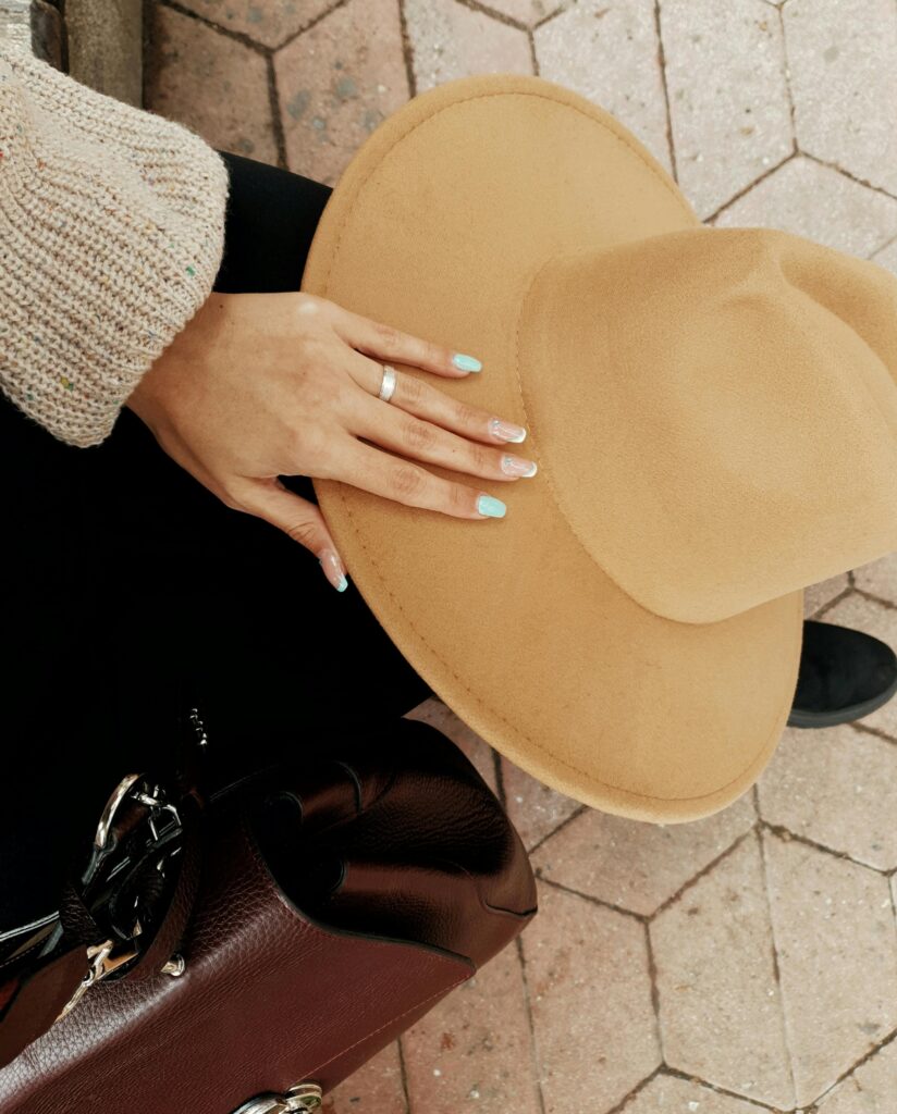 A faceless woman nails painted in light blue nail polish shade and classic French manicure putting her hand on a hat