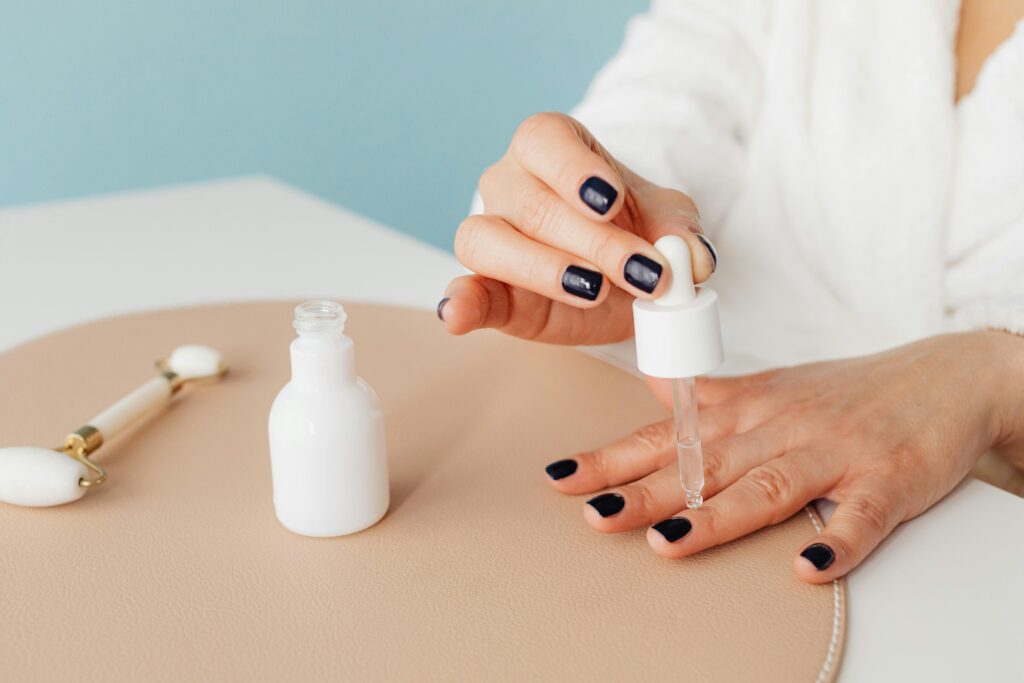 A faceless woman applying a nail moisturizer to her nails