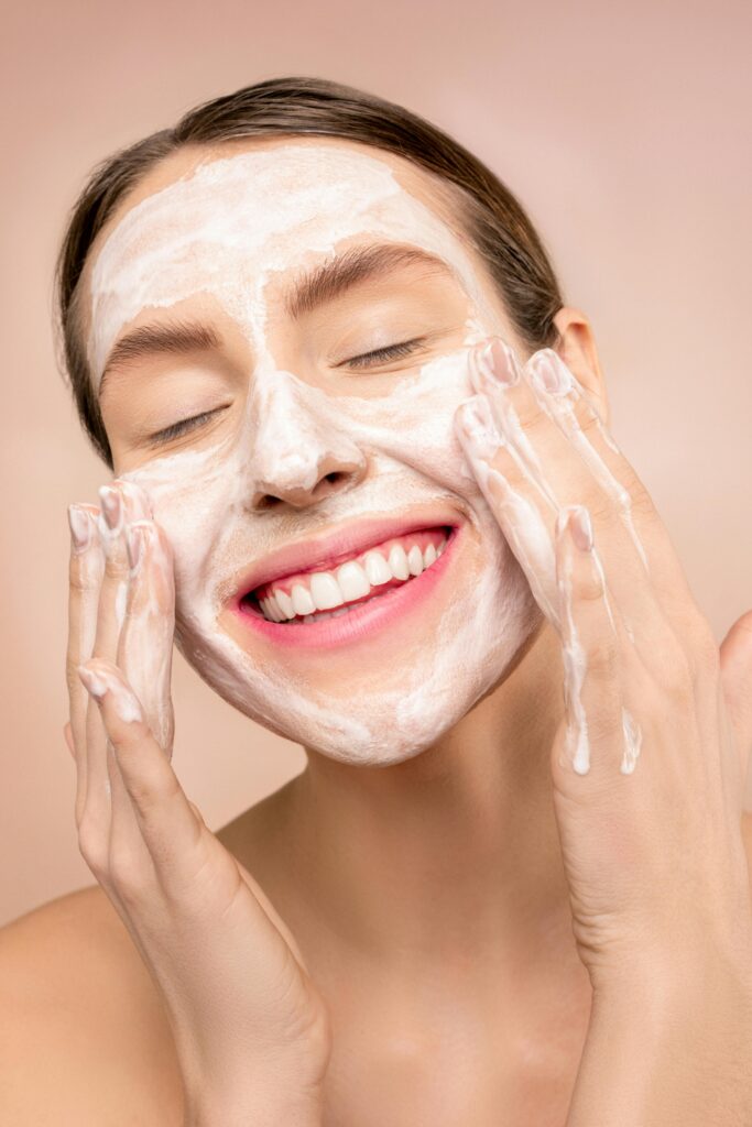 A beautiful, smiling woman is washing her face. Skincare, face care