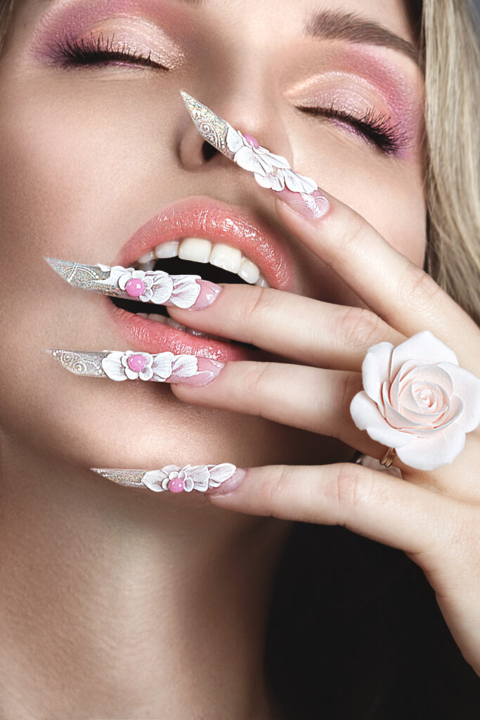 Beautiful blonde girl with long nails, perfect skin and a ring in the form of a flower. Picture taken in the studio. 2024 nail trends