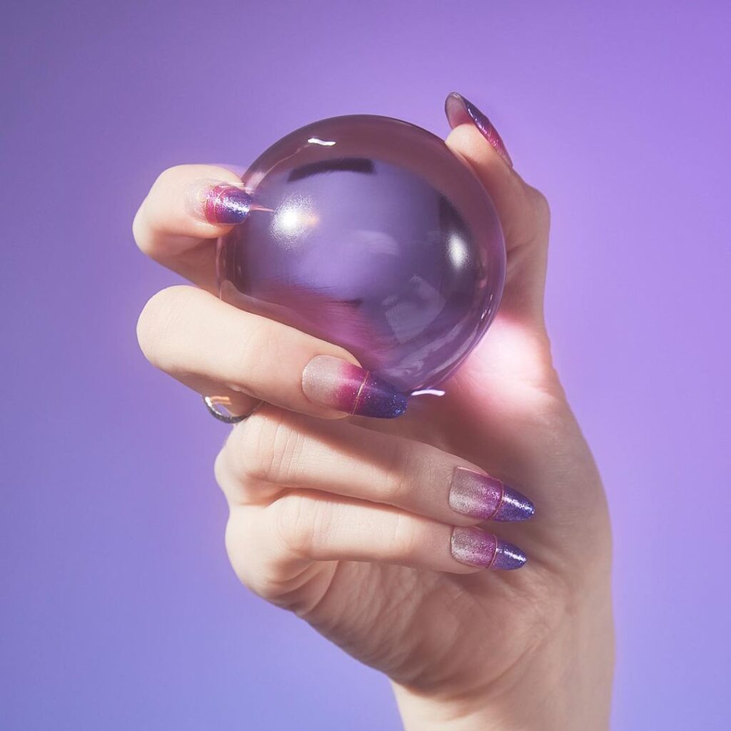 A faceless woman holding a ball her nails painted with Feelin' Libra-ted, a shimmery violet that’s the perfect balance of color, one of the OPI nail polish shades