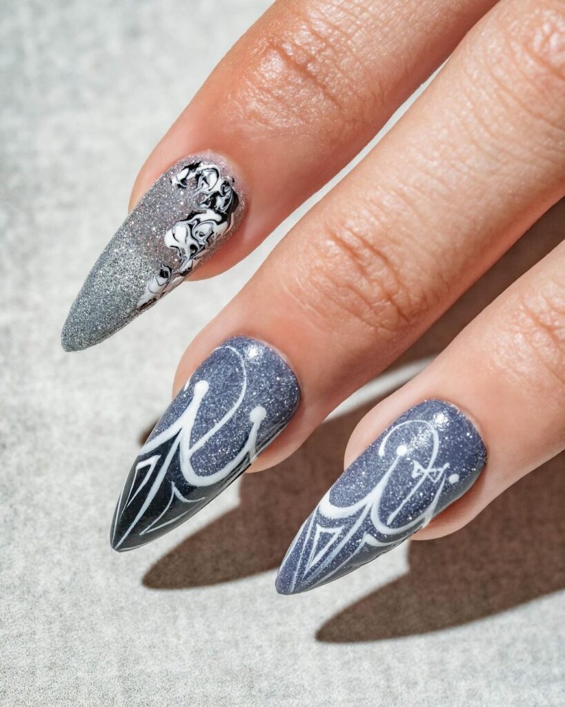 A faceless woman with nails painted in glitter designs featuring shades of gray, light blue, and white. These shimmery nails add a touch of glamour to any look. Glitter nails. Shimmery nails