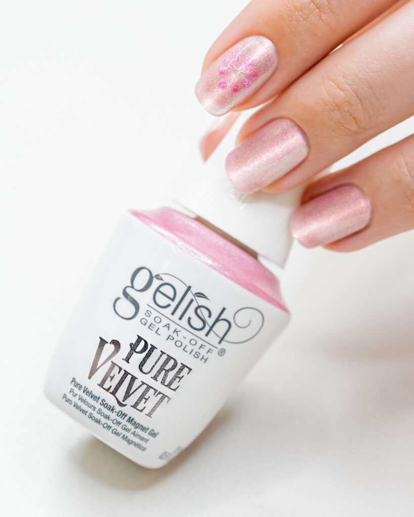 A woman's hand holding Gelish Pure Velvet nail bottle