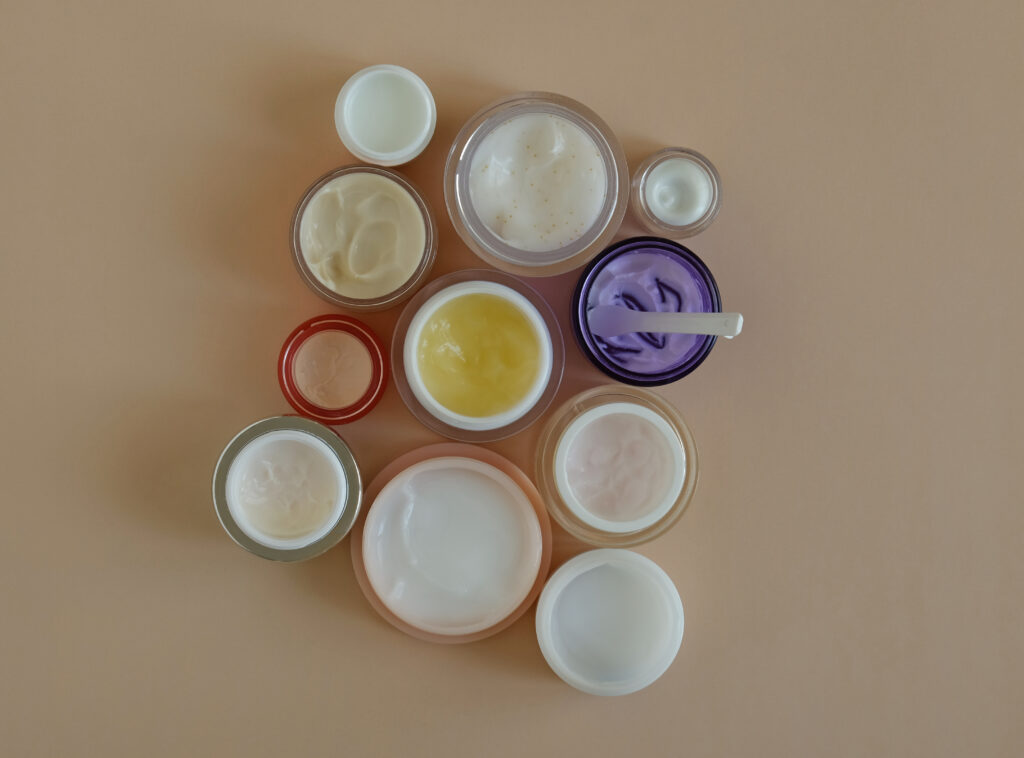 Face Moisturizer Types. Many jars of beauty cream or mask for face care on pastel background, top view. Concept of skincare cosmetic, cosmetic spa medical skin care. Natural cosmetics concept. Sunlight and shadow.