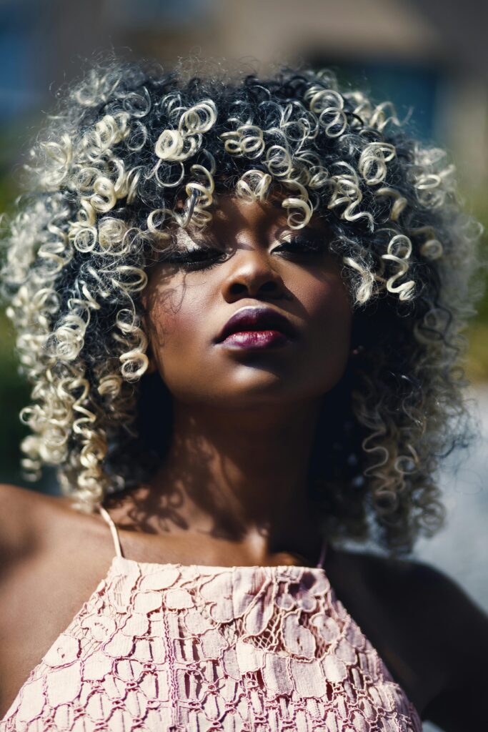 A beautiful black woman proudly shows off her healthy curly black and white hair, emphasizing the importance of hair treatments and care.